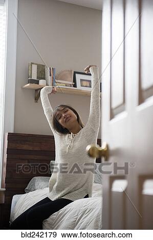 Mixed Race woman stretching arms on bed View Large Photo Image Stock Photo - Mixed Race woman stretching arms on bed. Fotosearch