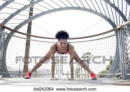 Picture - Mixed Race woman stretching leg near fence. Fotosearch