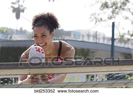 Stock Image - Mixed Race woman stretching leg on banister. Fotosearch