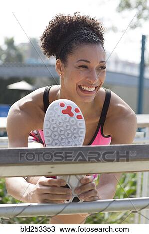 Stock Image - Mixed Race woman stretching leg on banister. Fotosearch