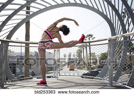 Stock Image - Mixed Race woman stretching leg on banister. Fotosearch