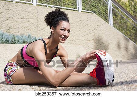 Mixed Race woman stretching legs on path View Large Photo Image Stock Photo - Mixed Race woman stretching legs on path. Fotosearch
