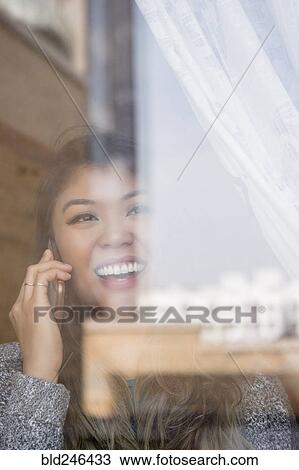 Mixed Race woman talking on cell phone behind window View Large Photo Image Stock Image - Mixed Race woman talking on cell phone behind window. Fotosearch