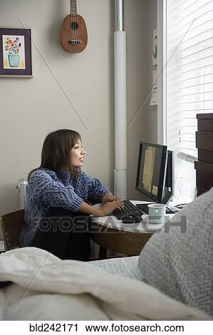 Mixed Race woman using computer near window in bedroom View Large Photo Image Stock Image - Mixed Race woman using computer near window in bedroom. Fotosearch