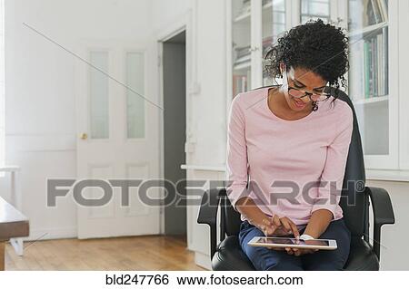 Stock Photograph - Mixed Race woman using digital tablet. Fotosearch
