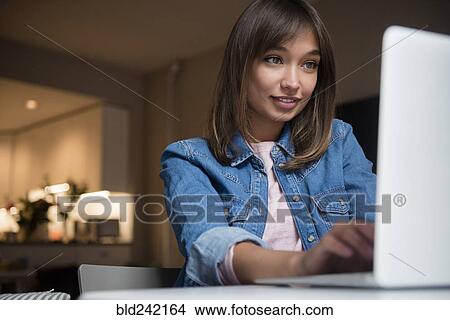 Picture - Mixed Race woman using laptop. Fotosearch