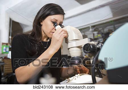 Stock Photo - Mixed Race woman using microscope. Fotosearch