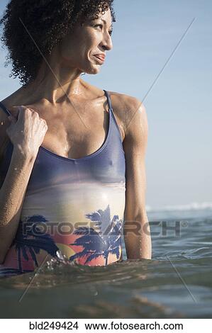 Picture - Mixed Race woman wading in ocean. Fotosearch