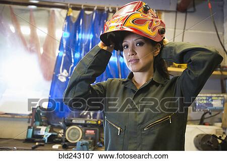 Stock Photo - Mixed Race woman wearing protective mask in workshop. Fotosearch