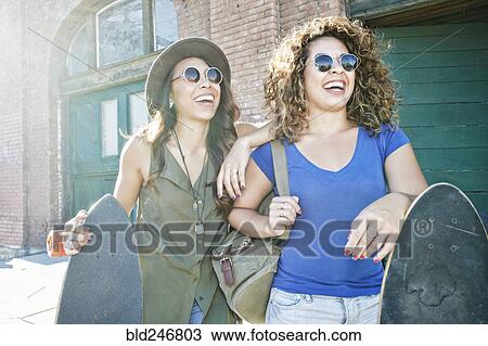 Mixed Race women holding skateboards in city View Large Photo Image Stock Image - Mixed Race women holding skateboards in city. Fotosearch