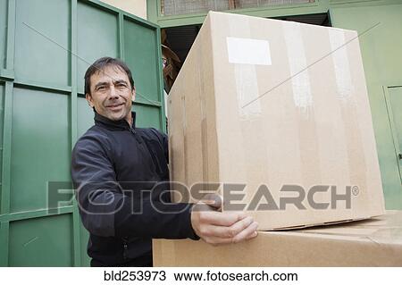 Stock Image - Mixed Race worker lifting cardboard box. Fotosearch