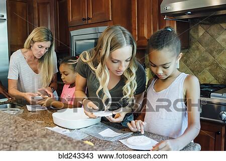 Mother and daughters cooking in domestic kitchen View Large Photo Image Stock Image - Mother and daughters cooking in domestic kitchen. Fotosearch