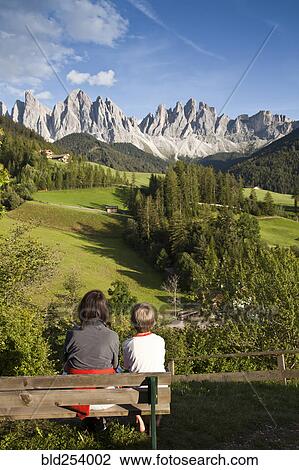 Stock Image - Mother and son sitting on bench admiring scenic view of mountains. Fotosearch