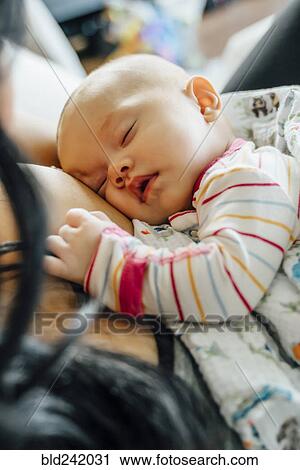 Stock Image - Mother holding sleeping baby daughter. Fotosearch