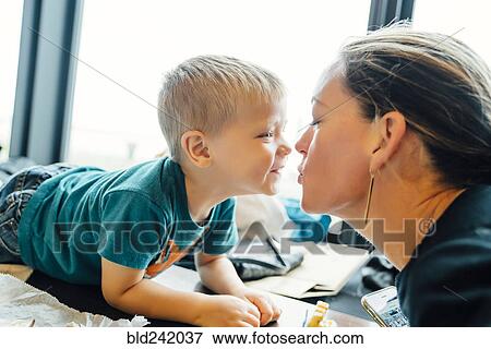 Mother kissing son laying on table View Large Photo Image Stock Photo - Mother kissing son laying on table. Fotosearch
