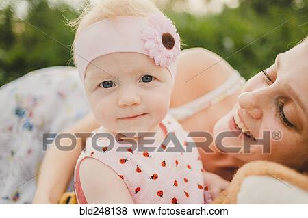 Stock Photo - Mother posing with baby daughter wearing headband. Fotosearch