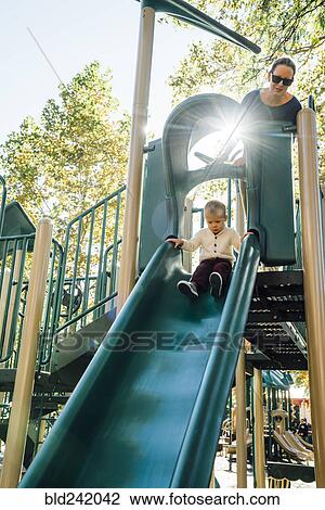 Mother watching son on playground slide View Large Photo Image Stock Image - Mother watching son on playground slide. Fotosearch