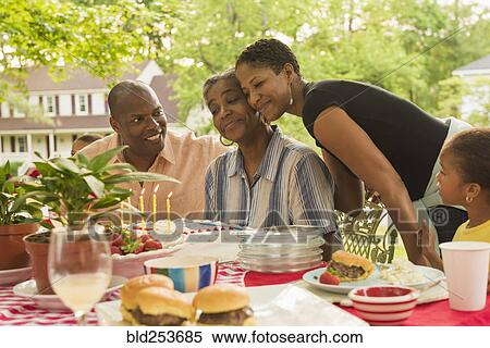 Stock Photography - Multi-generation family celebrating with cake at picnic. Fotosearch