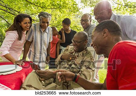 Stock Photography - Multi-generation family laughing at cell phone. Fotosearch