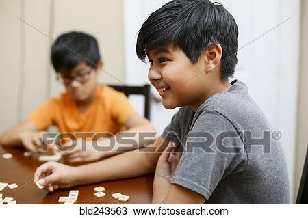 Stock Image - Native American boys playing spelling game at table. Fotosearch