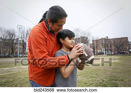 Stock Photo - Native American father teaching son to throw football. Fotosearch