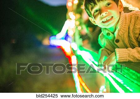Stock Photography - Neon lights glowing on face of Mixed Race boy. Fotosearch