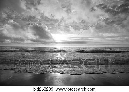 Stock Photo - Ocean waves on beach at sunset. Fotosearch