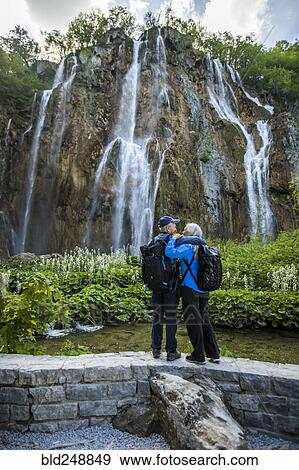 Stock Photo - Older Caucasian couple hugging near waterfall. Fotosearch