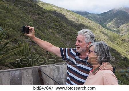 Stock Photo - Older Caucasian couples posing for cell phone selfie. Fotosearch
