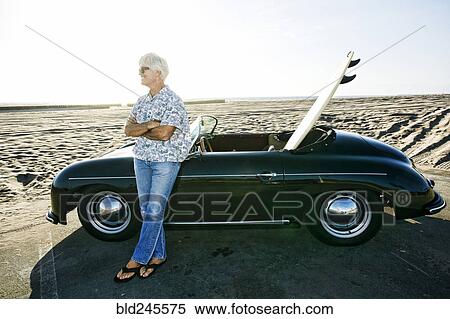 Older Caucasian man leaning on convertible car with surfboard on beach View Large Photo Image Stock Photography - Older Caucasian man leaning on convertible car with surfboard on beach. Fotosearch