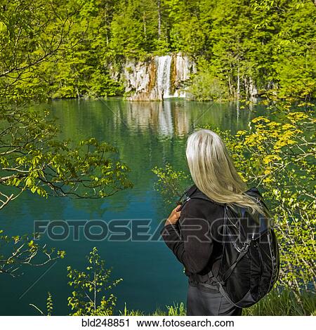 Stock Image - Older Caucasian woman admiring waterfall. Fotosearch