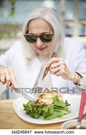Older Caucasian woman cutting food on plate View Large Photo Image Stock Photo - Older Caucasian woman cutting food on plate. Fotosearch