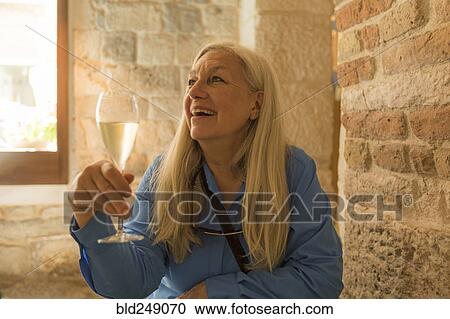 Stock Image - Older Caucasian woman drinking white wine. Fotosearch