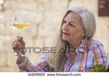 Older Caucasian woman examining white wine View Large Photo Image Picture - Older Caucasian woman examining white wine. Fotosearch