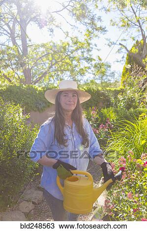 Stock Image - Older Caucasian woman holding watering can. Fotosearch