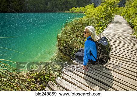 Older Caucasian woman sitting on wooden pathway near water View Large Photo Image Stock Photo - Older Caucasian woman sitting on wooden pathway near water. Fotosearch