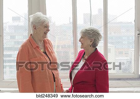Stock Photo - Older Caucasian women laughing near window. Fotosearch