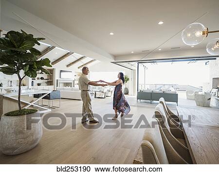 Stock Image - Older couple dancing in modern home. Fotosearch