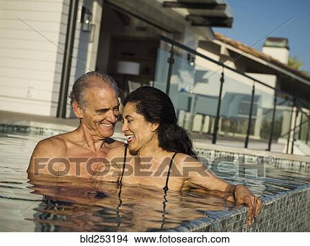 Picture - Older couple laughing in swimming pool. Fotosearch