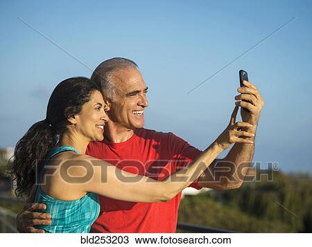 Stock Image - Older couple posing for cell phone selfie. Fotosearch