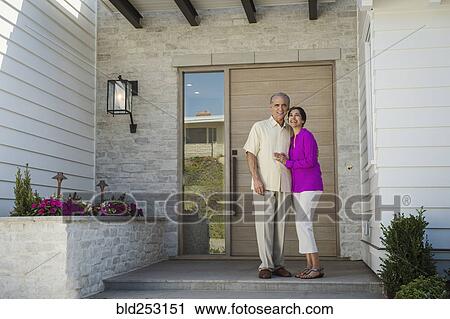 Stock Image - Older couple posing on front stoop of house. Fotosearch