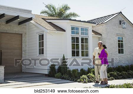 Stock Photo - Older couple standing near driveway of house. Fotosearch
