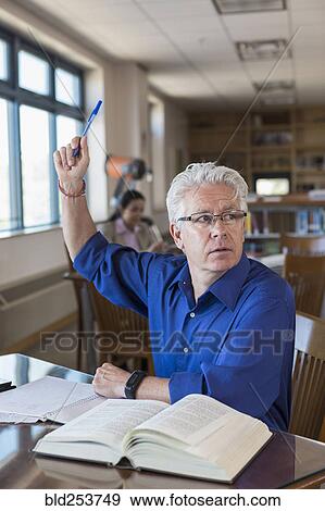Stock Photo - Older man in library raising hand and asking question. Fotosearch