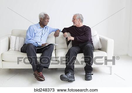 Older men reading magazines sitting on sofa View Large Photo Image Stock Image - Older men reading magazines sitting on sofa. Fotosearch