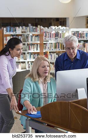 Stock Photography - Older people using computer in library. Fotosearch