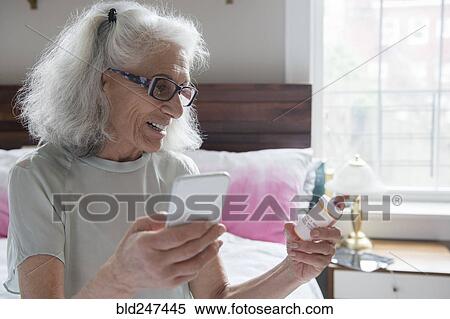 Stock Photography - Older woman checking prescription with cell phone. Fotosearch