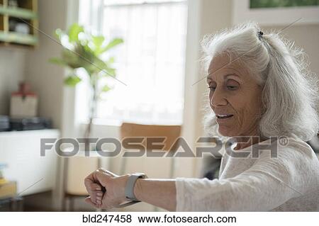 Stock Photo - Older woman checking wristwatch. Fotosearch