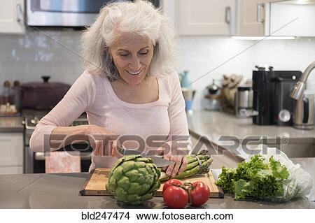 Picture - Older woman chopping asparagus. Fotosearch