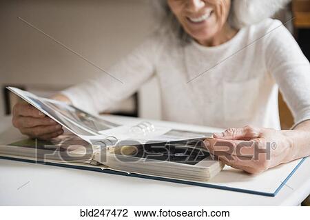 Older woman enjoying a photo album View Large Photo Image Stock Image - Older woman enjoying a photo album. Fotosearch