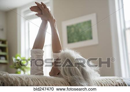 Stock Image - Older woman stretching with arms raised. Fotosearch